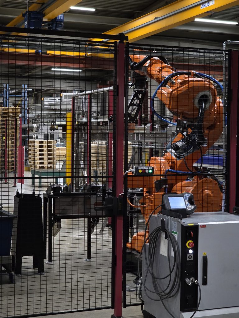 Den renoverade roboten i sin skyddade arbetscell, redo för automatiserad materialhantering.