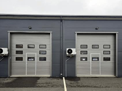 Grå plåtfasad med två garagedörrar